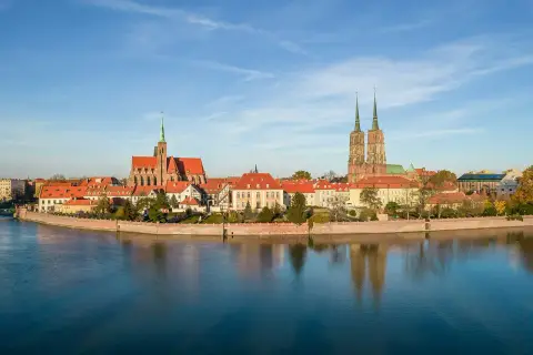 Wrocław co zwiedzić? Katedra św. Jana Chrzciciela i kościół św. Krzyża na Ostrowie Tumskim, odbijające się w spokojnej wodzie Odry.